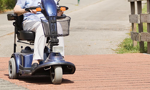 Image of three wheeled mobility scooter driving down the road