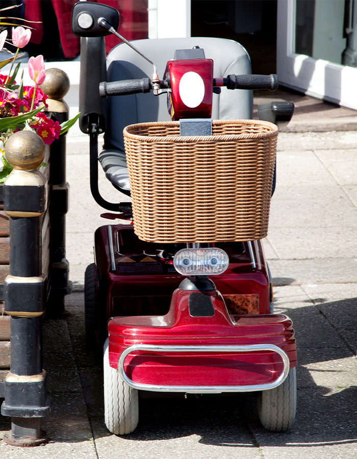 Image of a four wheeled mobility scooter parked on a sidewalk