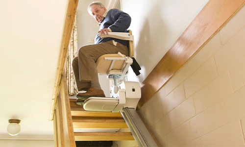 older man going down straight stair lift